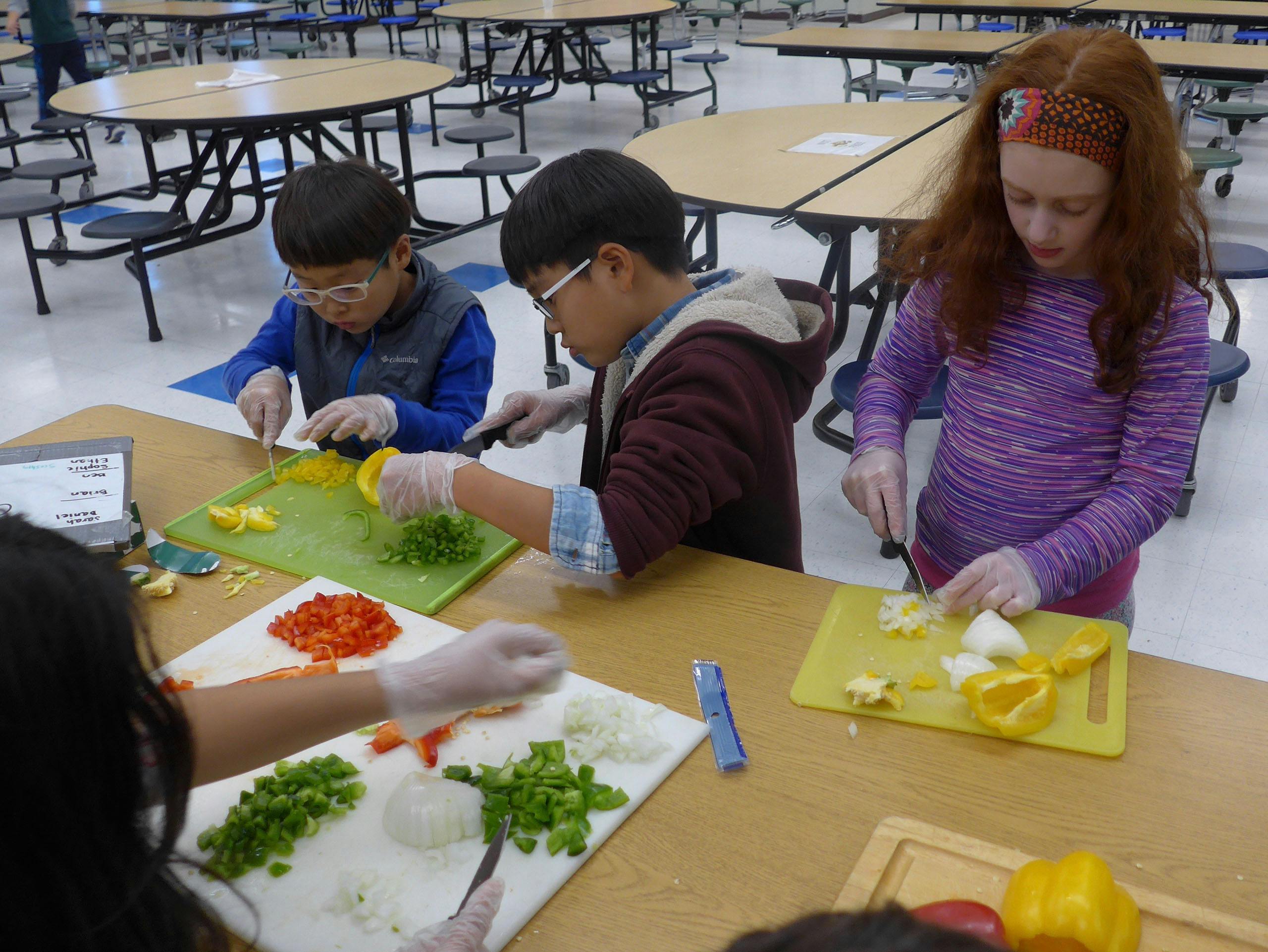 Children chopping vegetables on cutting boards
