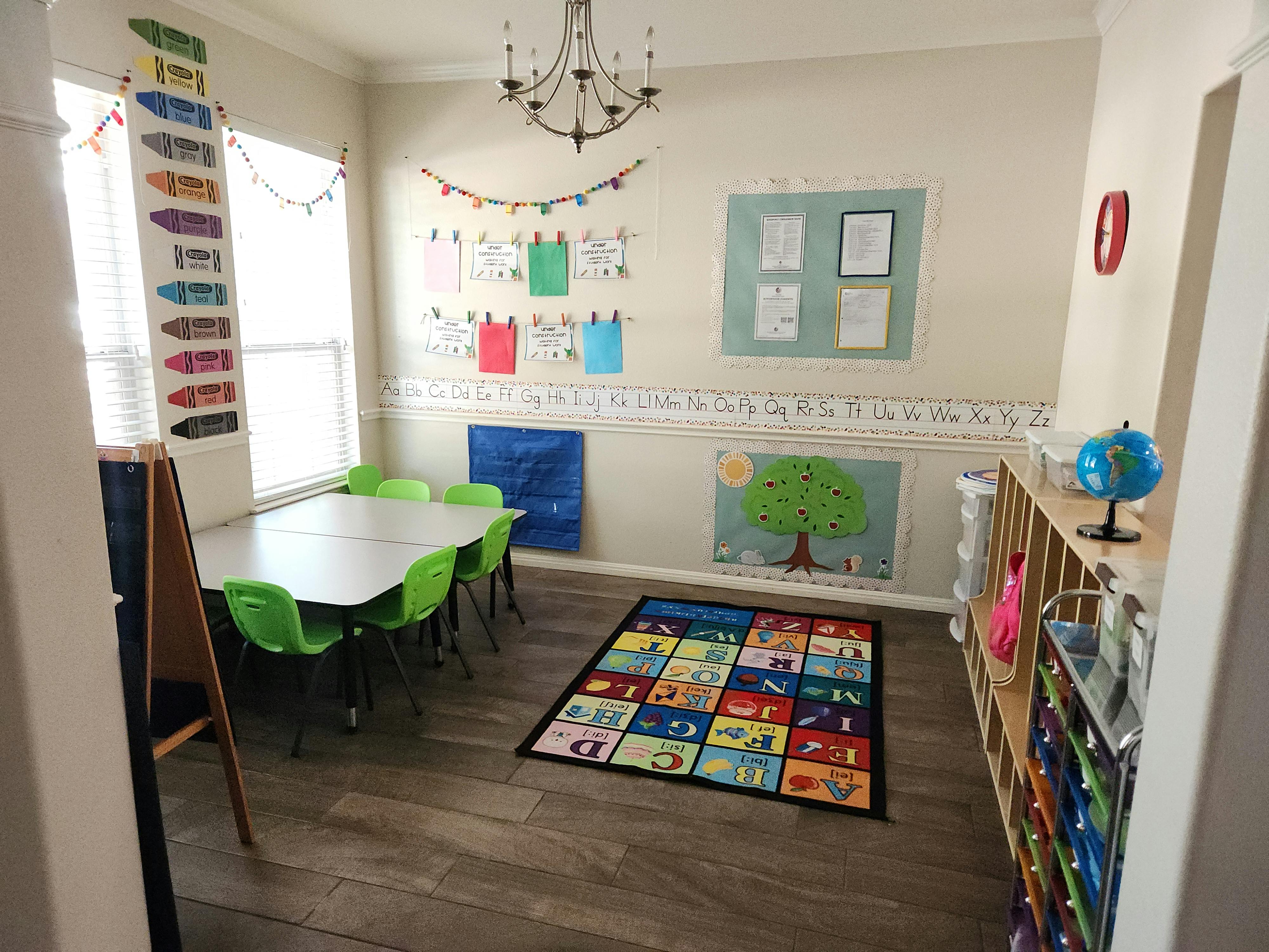 Classroom with a table and chairs, alphabet rug, and decorations on the walls