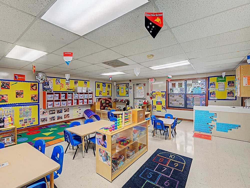 An empty classroom with small tables and chairs, colorful decorations on walls