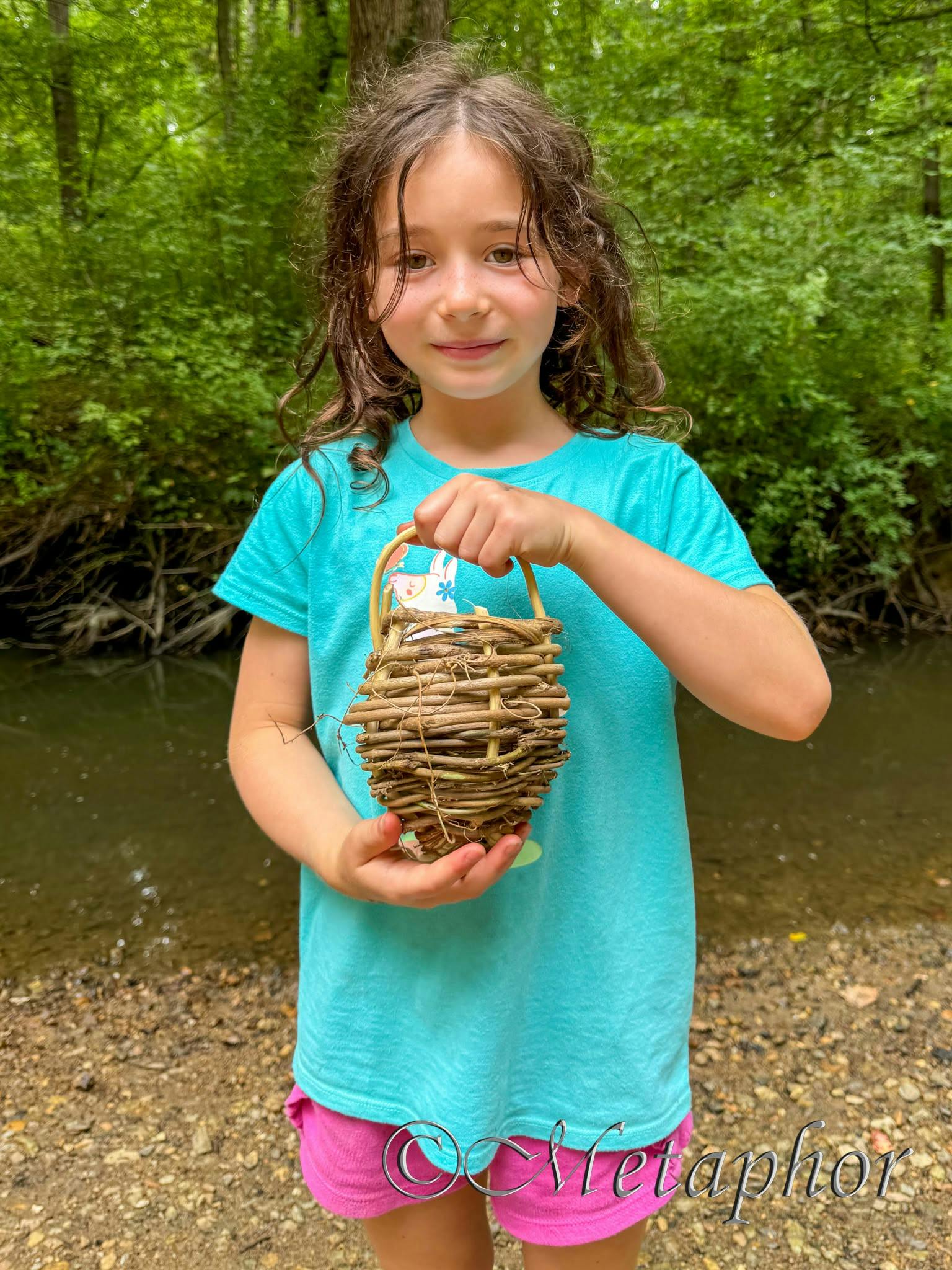 Child holding a small woven basket near a stream