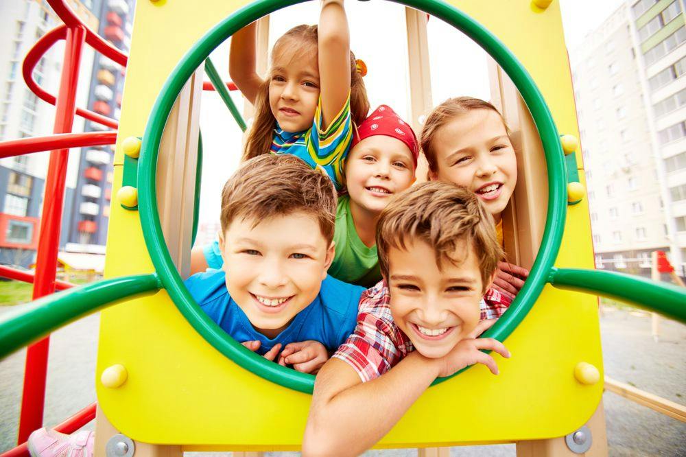 Five children looking through an opening on a playground structure