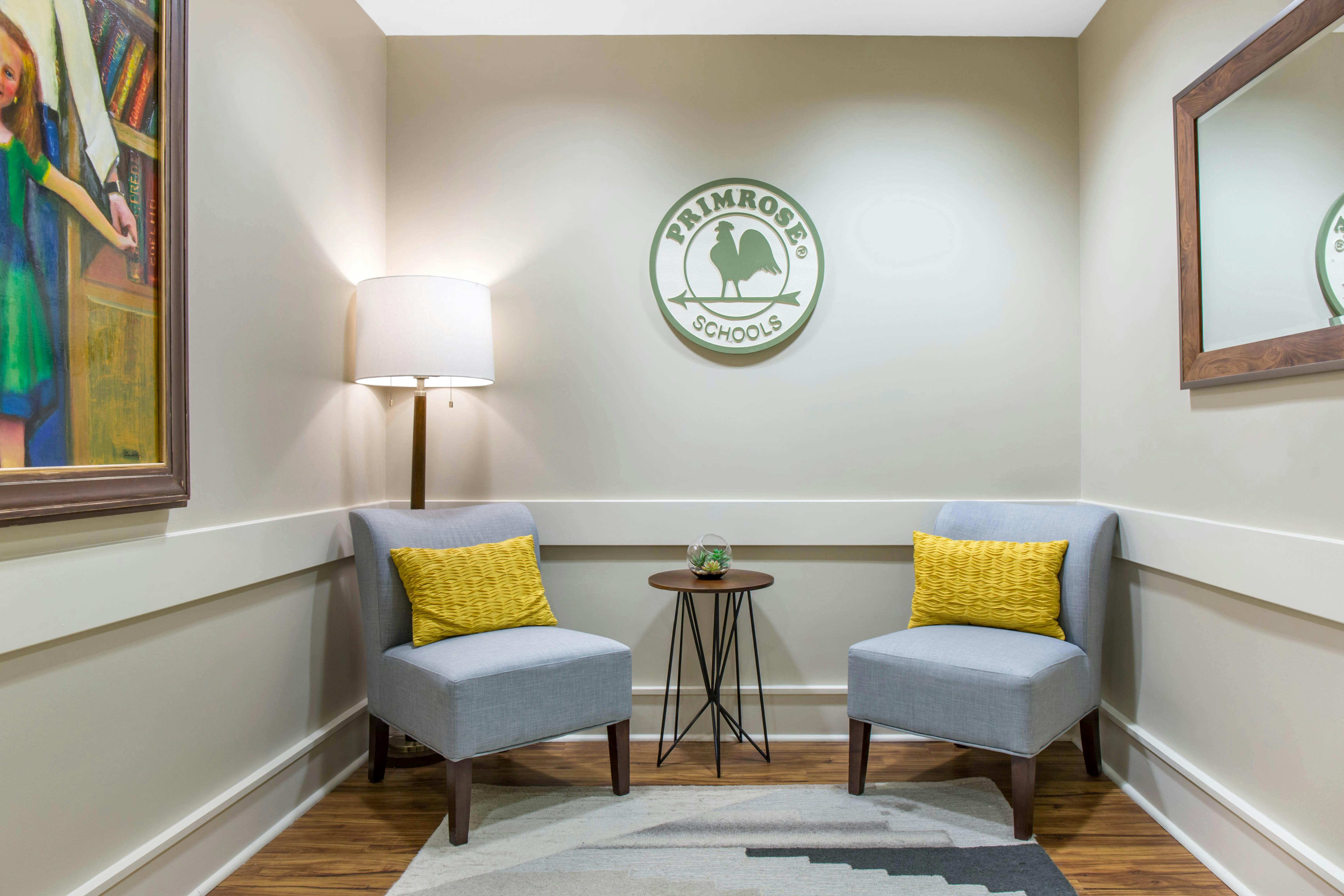 Two armless upholstered chairs with yellow pillows and a round side table