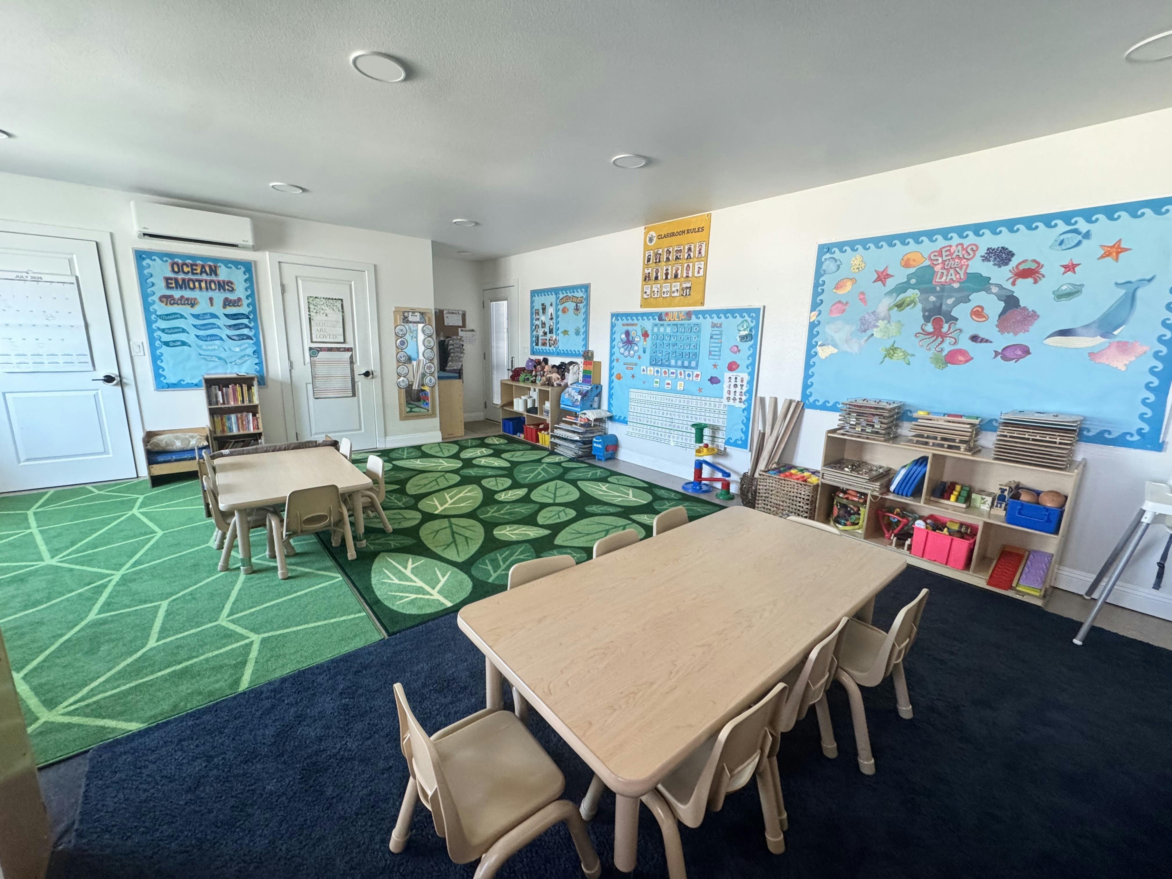 Classroom interior with small tables and chairs on a patterned rug