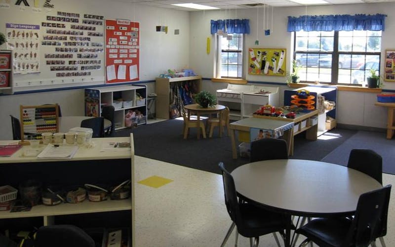 An empty early childhood classroom with activity centers and small tables