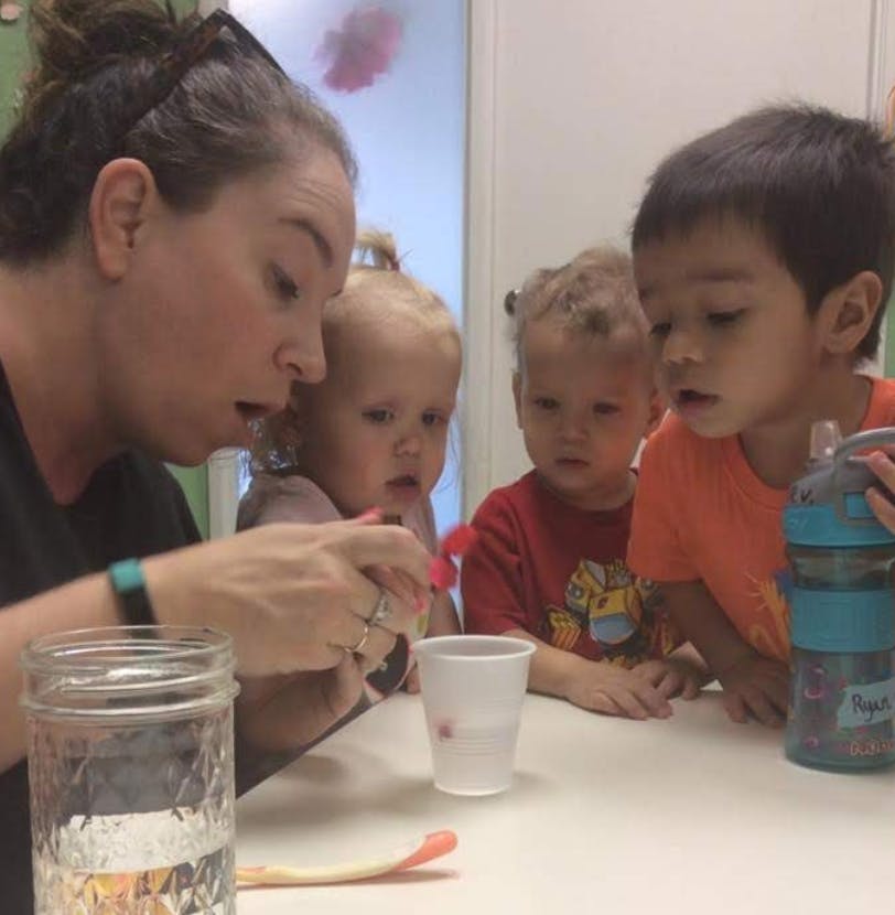 Person and three children looking at something on a table