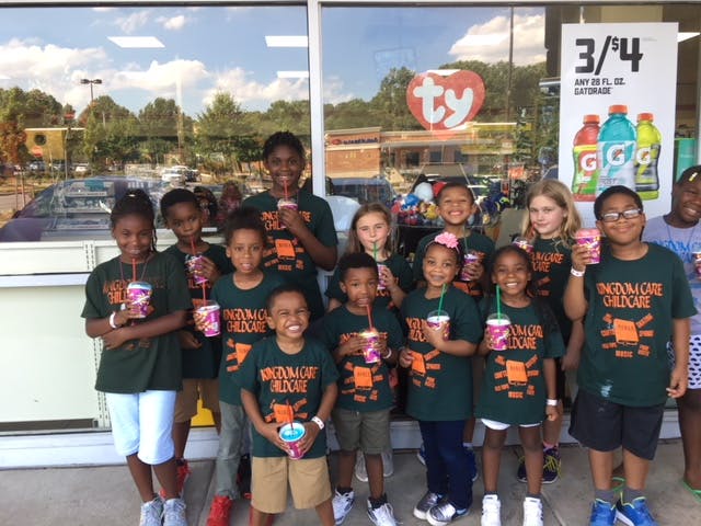 Group of children and teens in matching shirts holding drinks