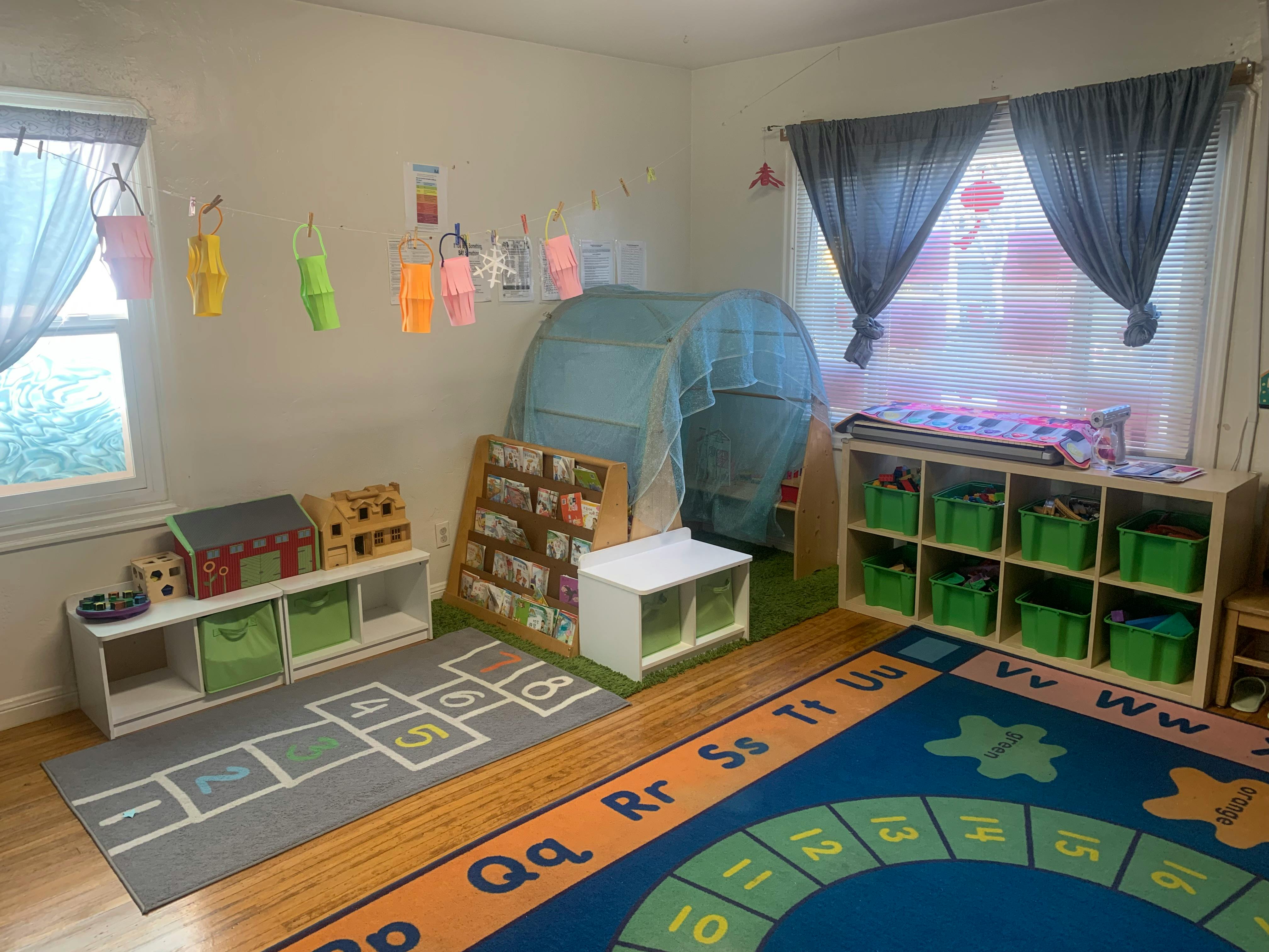 Playroom with a hopscotch rug, alphabet rug, and toy storage shelves