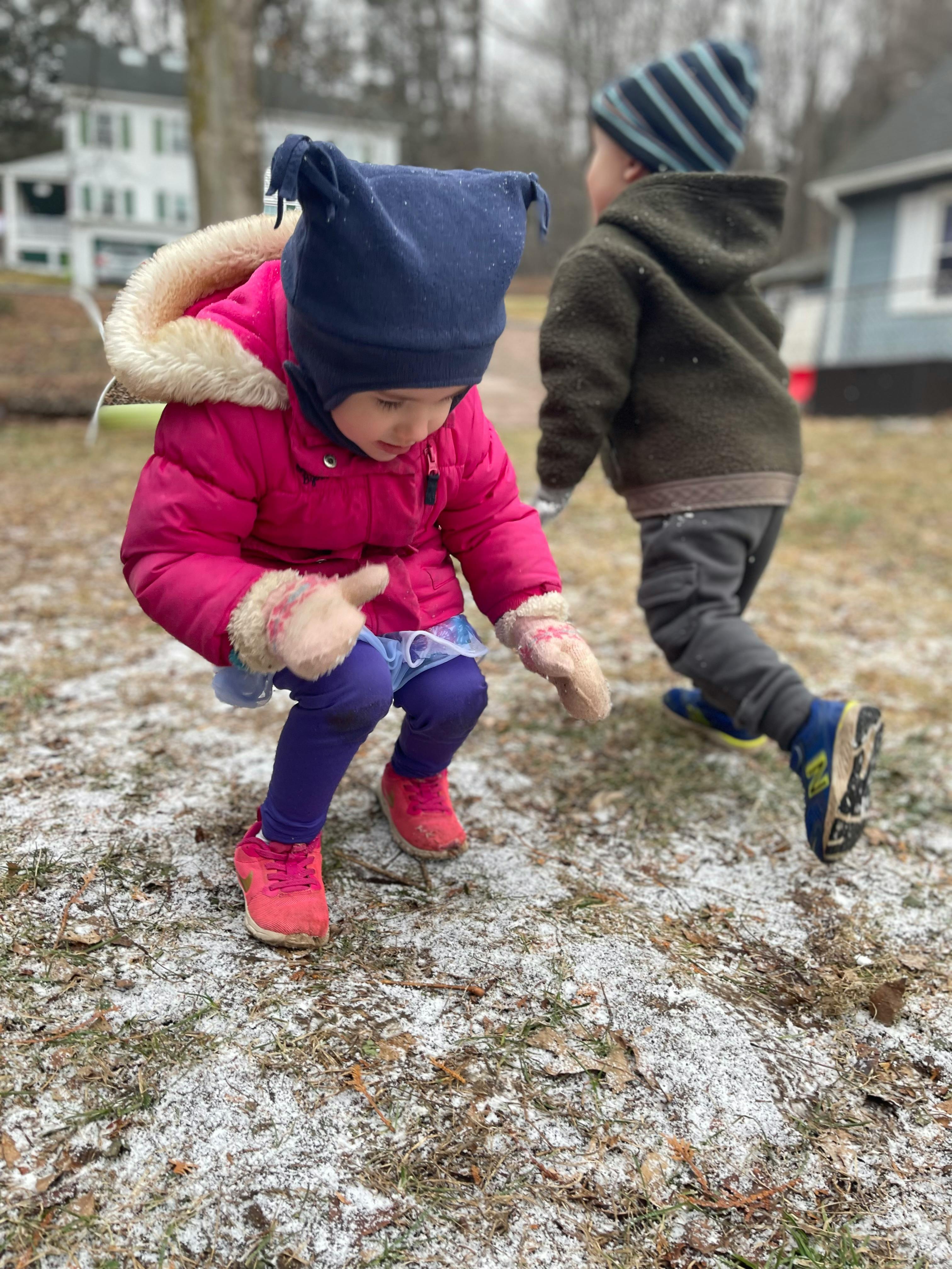 Two children playing outdoors in light snow