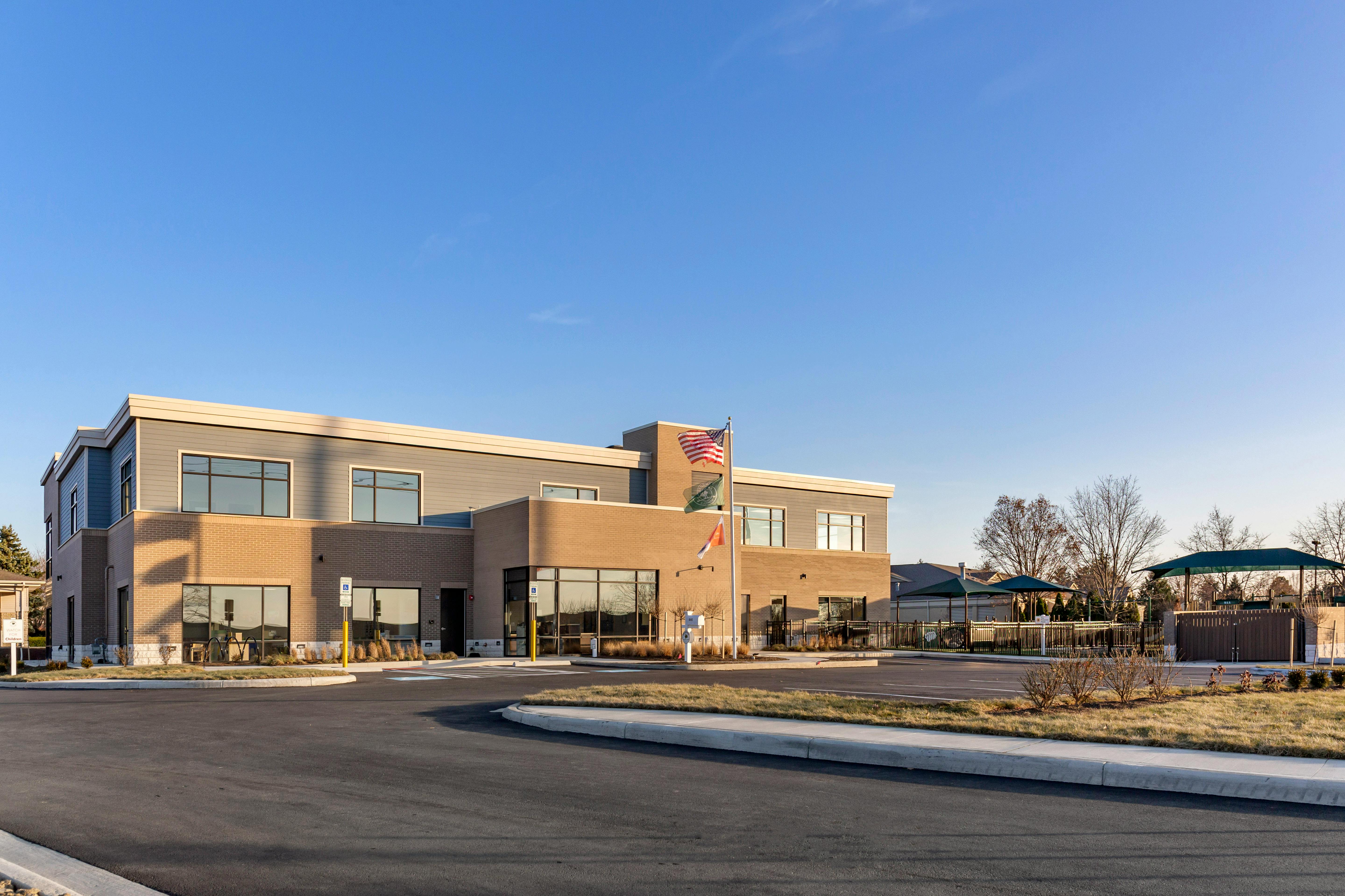 Modern two-story building with brick and siding facade, parking lot, and flagpole