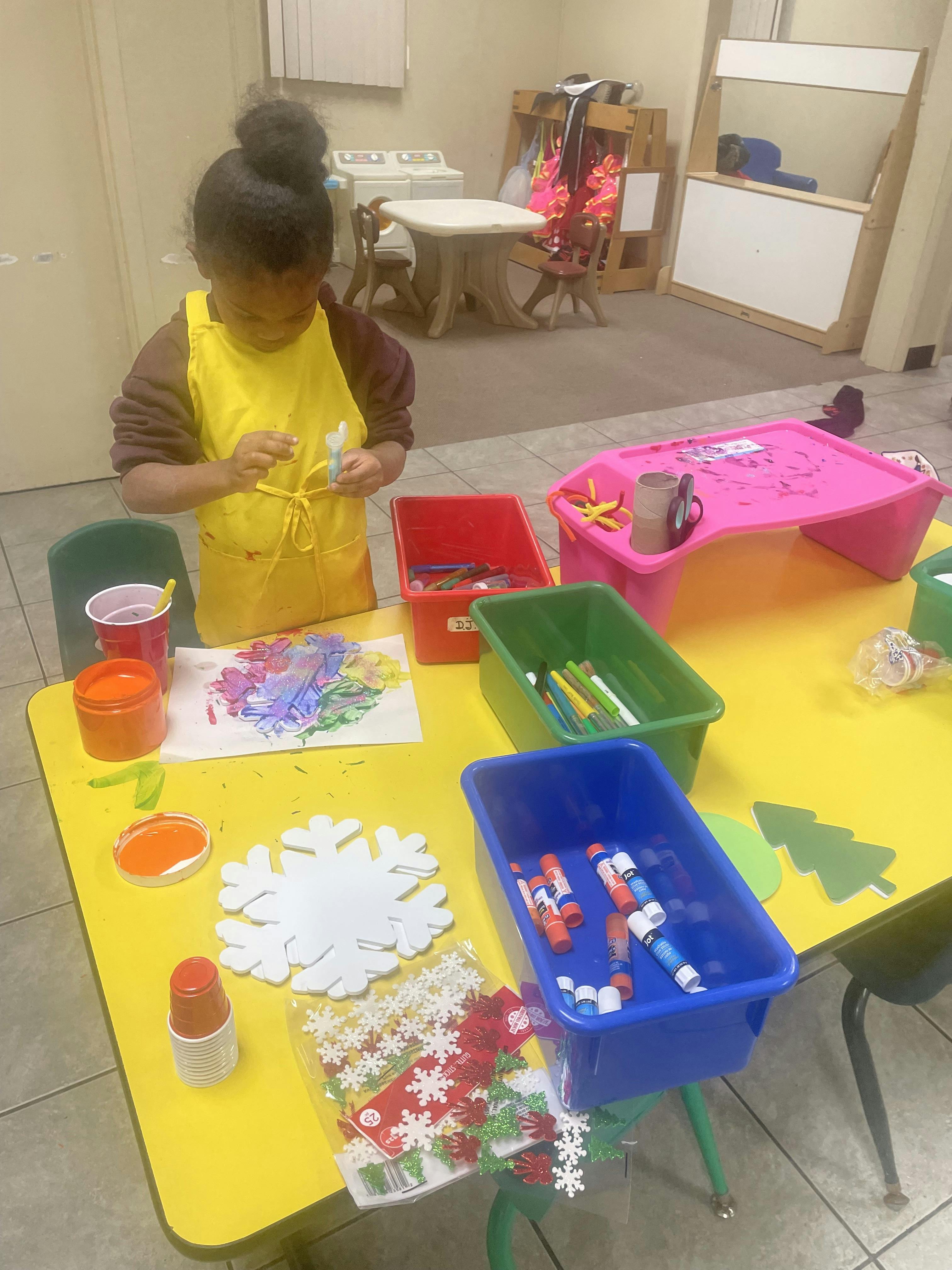 Child wearing an apron working on a craft project at a table