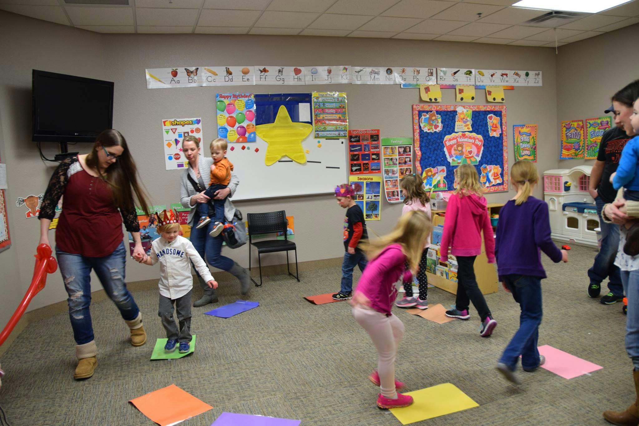 Adults and children in a room with colorful papers on the floor