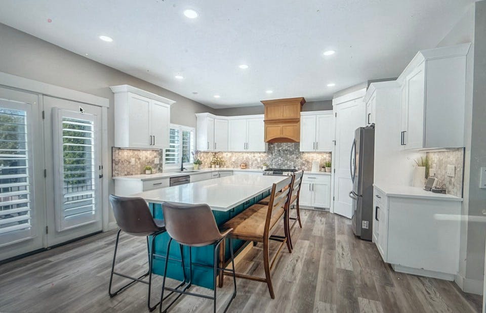 Kitchen with white cabinets, a large island, and bar stools