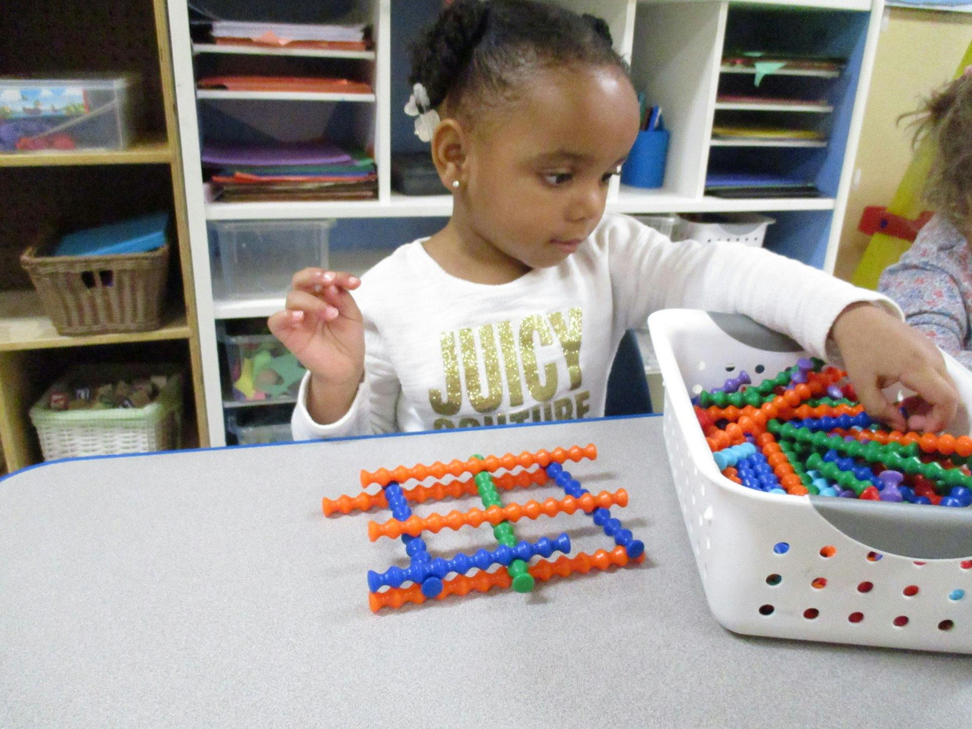 Child playing with colorful interlocking building toys in a classroom