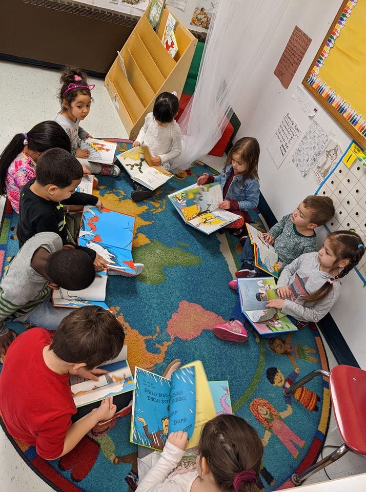 Children sitting on a rug reading books in a classroom