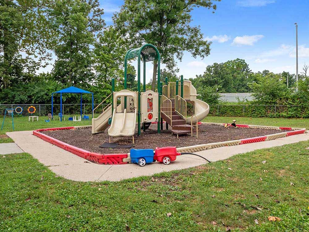 A children's playground with slides, stairs, and a swing set surrounded by mulch