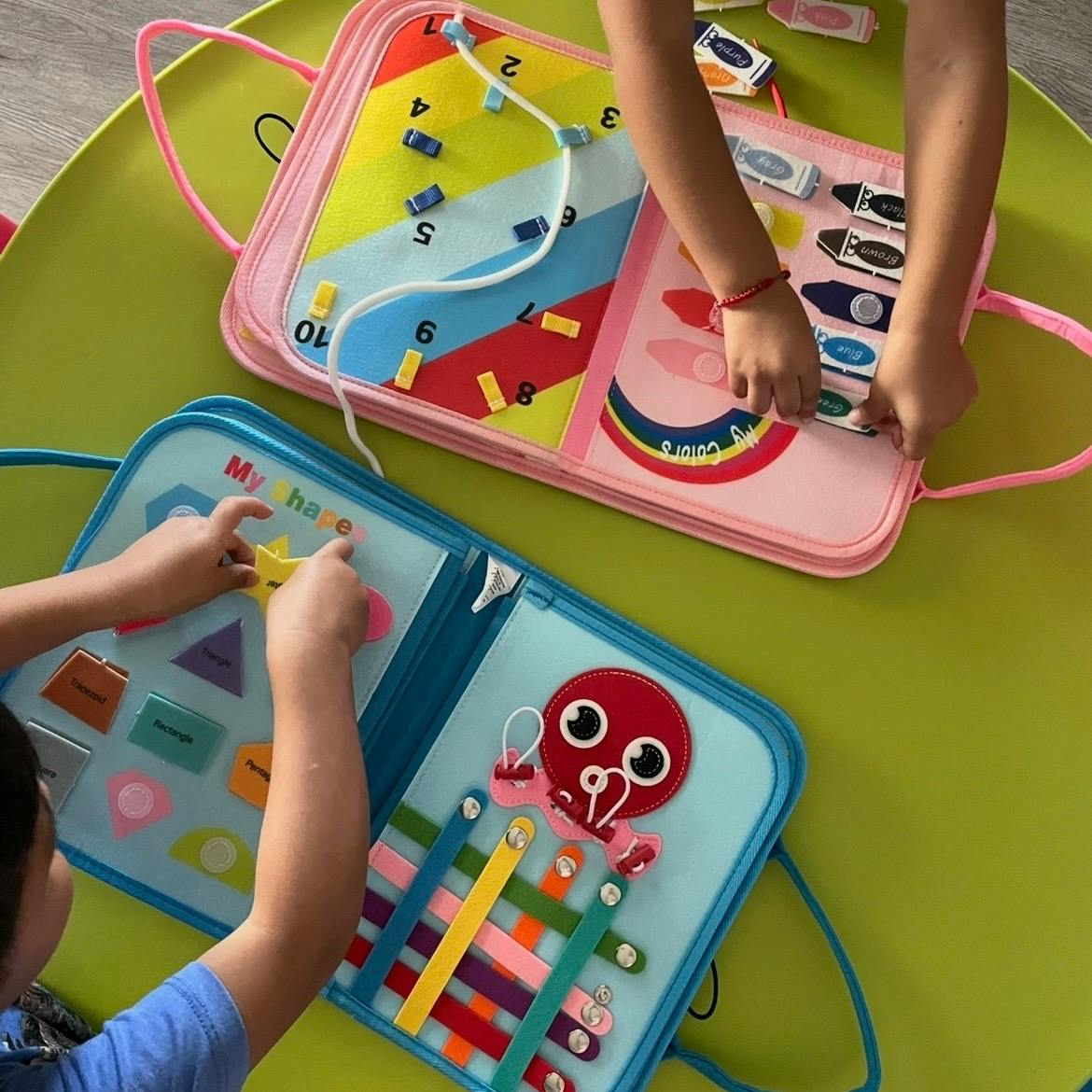 Children playing with educational felt activity boards on a green table