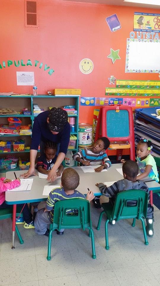 Person helping children at a table in a classroom