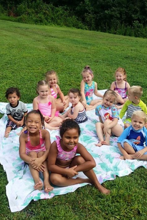 Group of children sitting on a blanket on grass