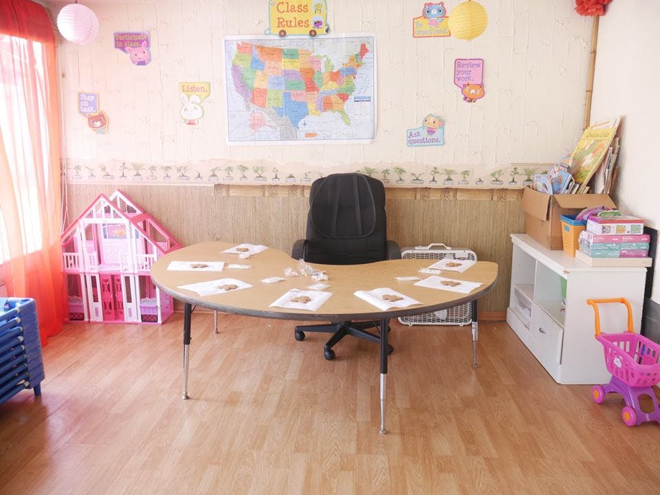 Classroom with a large table, chair, dollhouse, and map on the wall