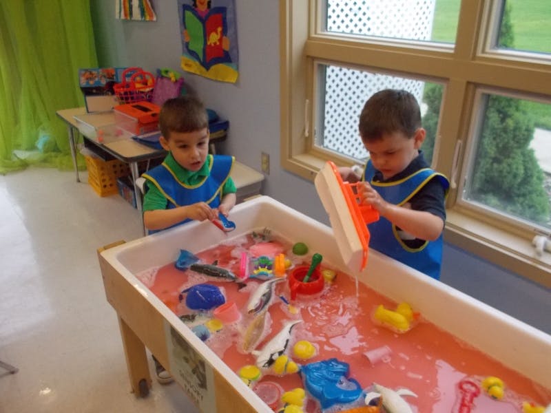 Two children playing with toys in a water table