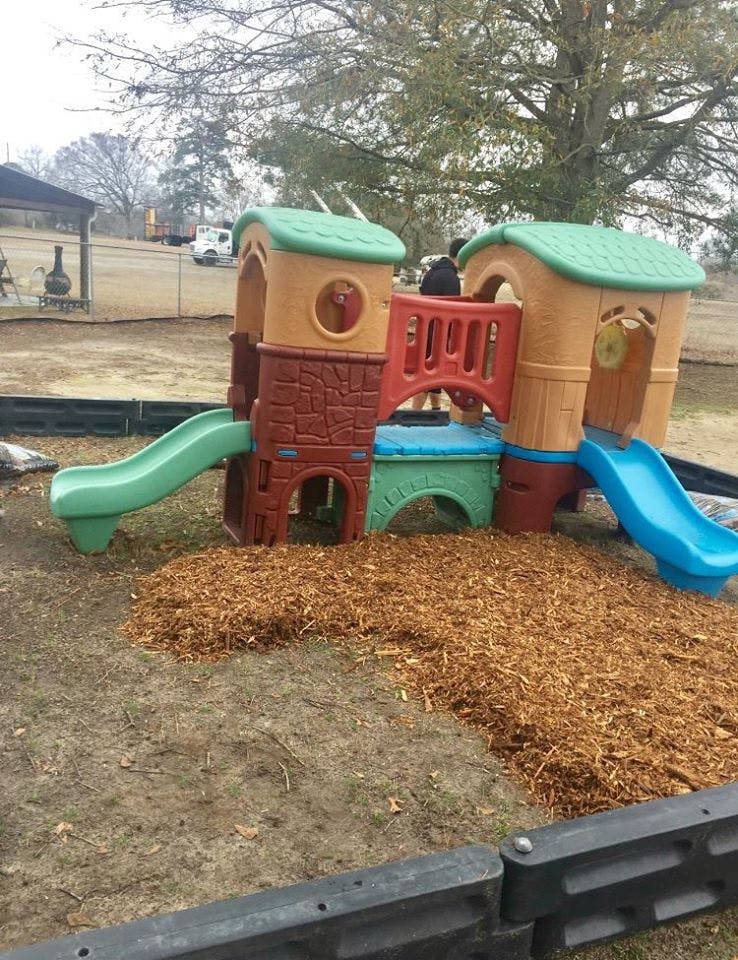 Plastic playground structure with slides and wood chips on the ground