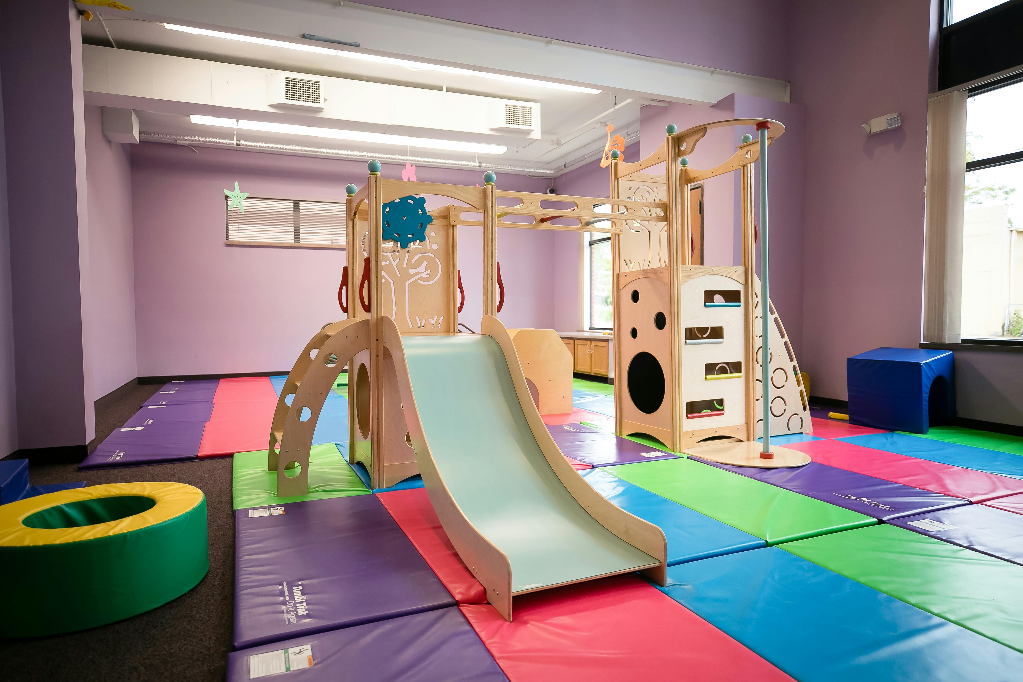 Indoor playground with slide and climbing structure on colorful mats
