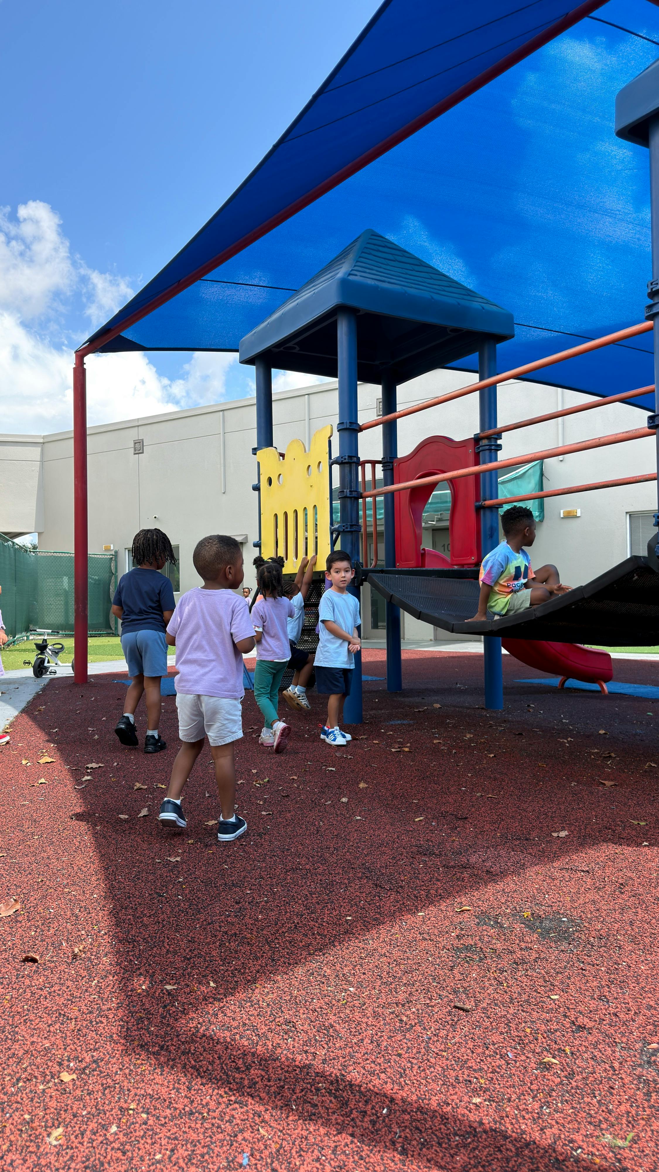 Children playing on a playground equipment structure under a blue canopy