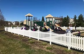 Playground with white fence and children playing