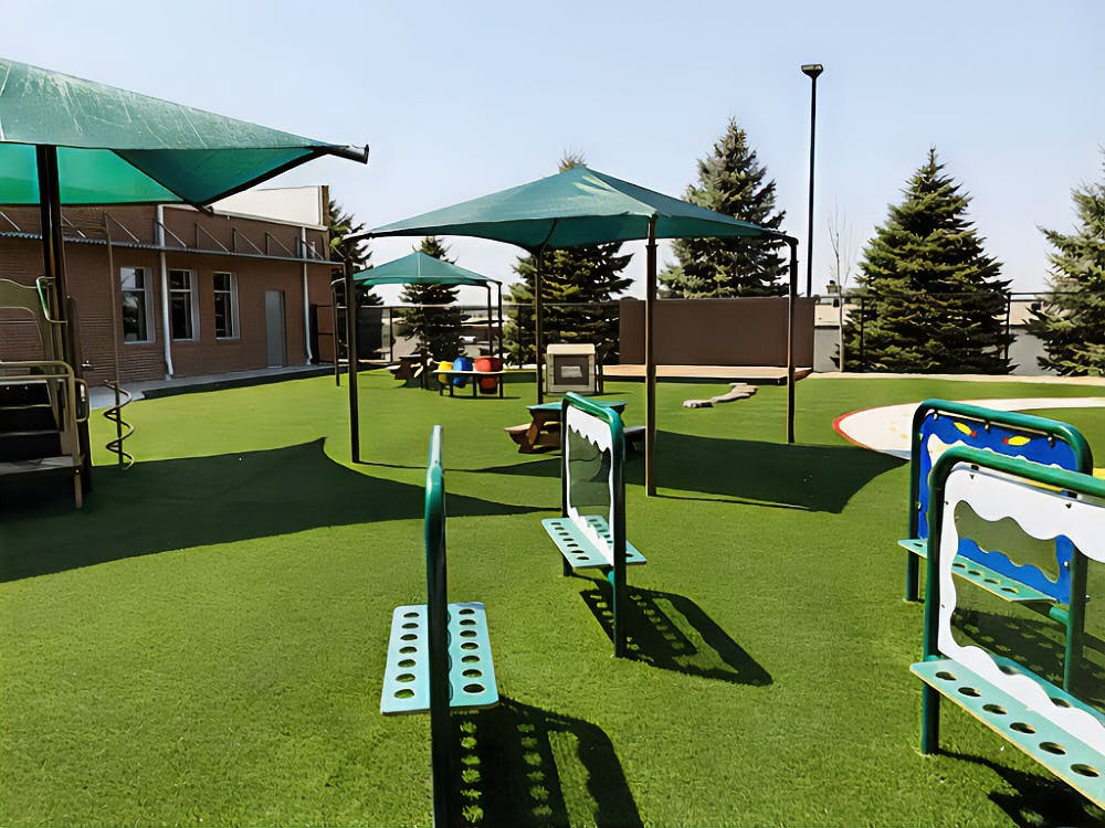 Empty playground with artificial turf, shade covers, and play equipment