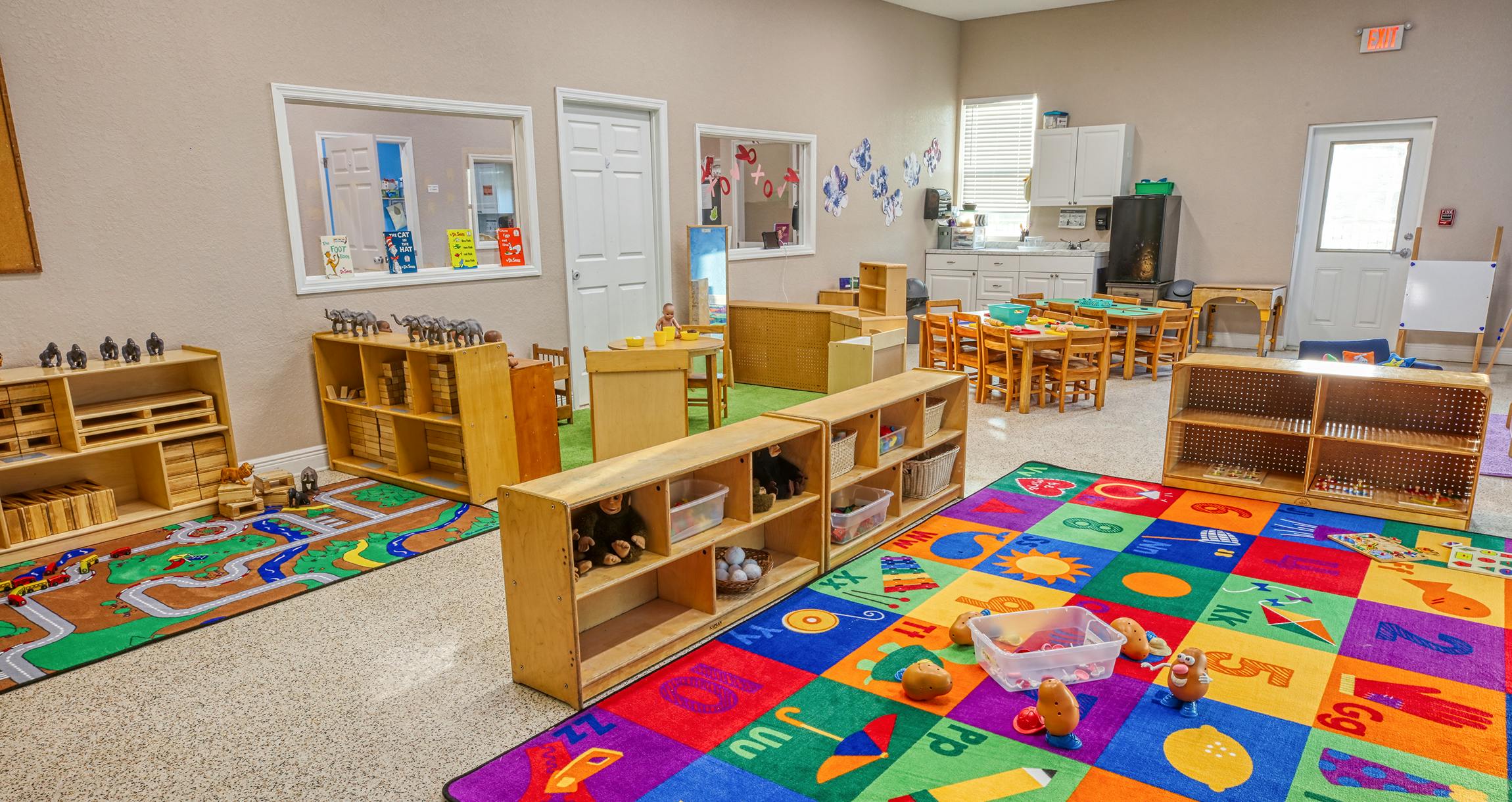 Children's classroom with colorful alphabet rug, small tables, and shelves of toys