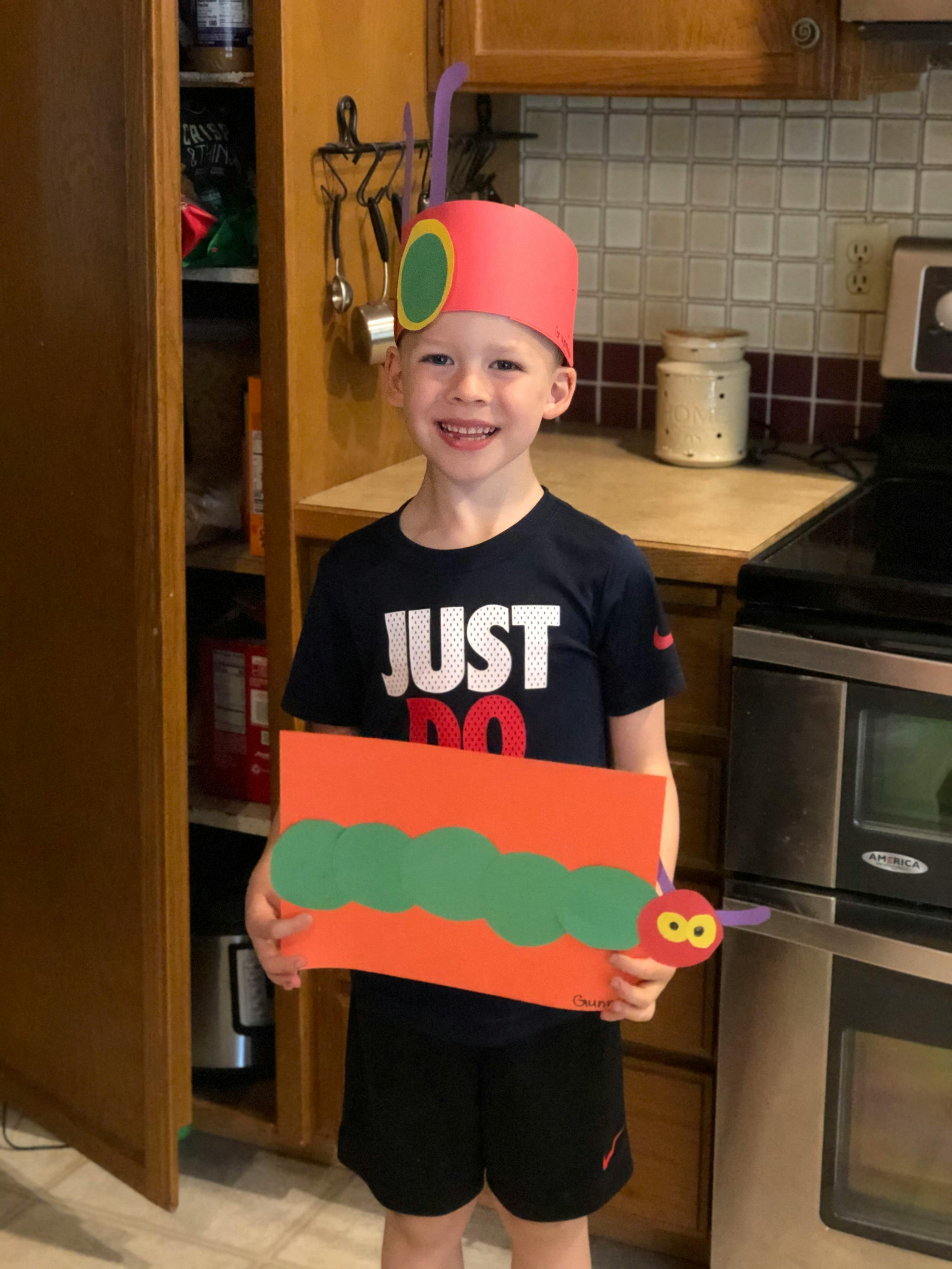 Child wearing a caterpillar hat and holding a caterpillar craft