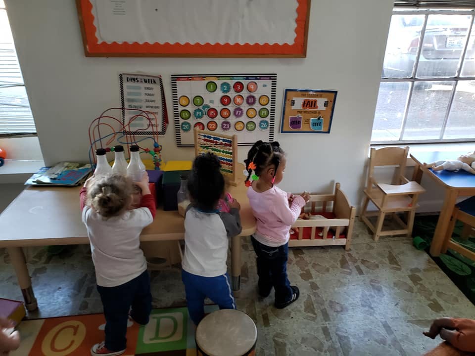 Three children playing with toys in a classroom