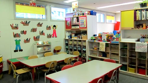 Classroom with tables, chairs, and shelves with learning materials