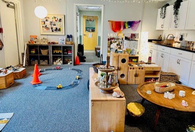 Playroom with toy cars on a track, play kitchen, and small wooden table