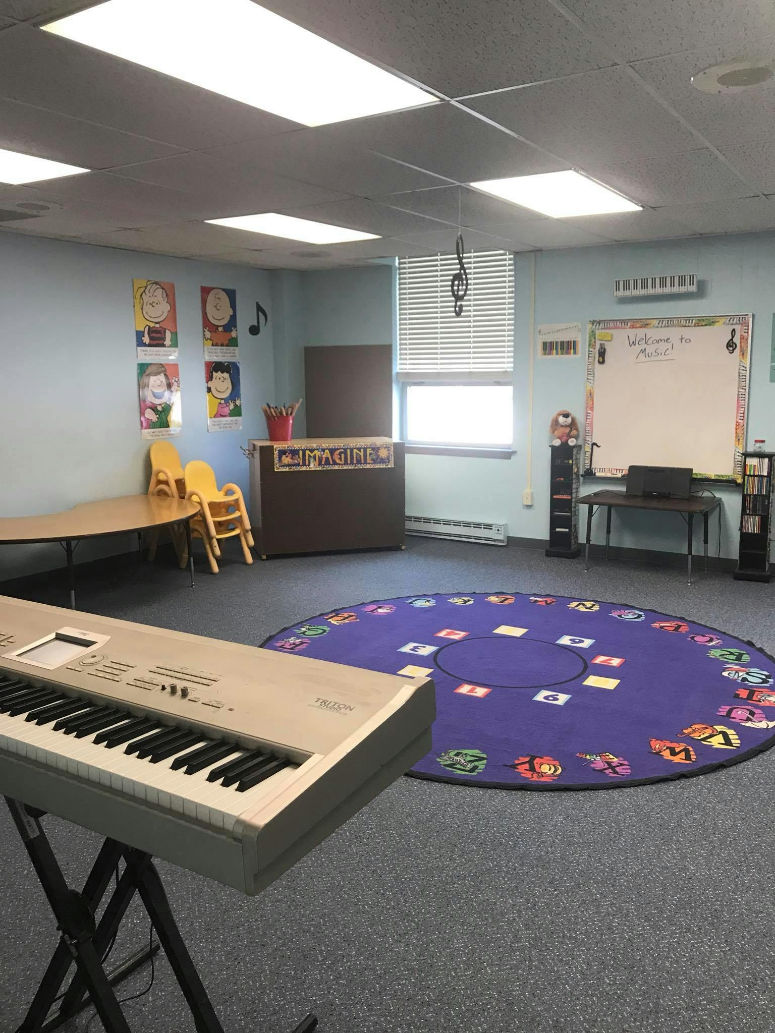 Music classroom with a keyboard, round rug, and whiteboard