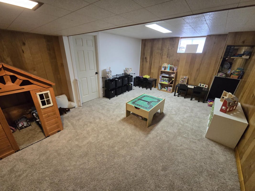 Basement room with a playhouse, game table, and storage units