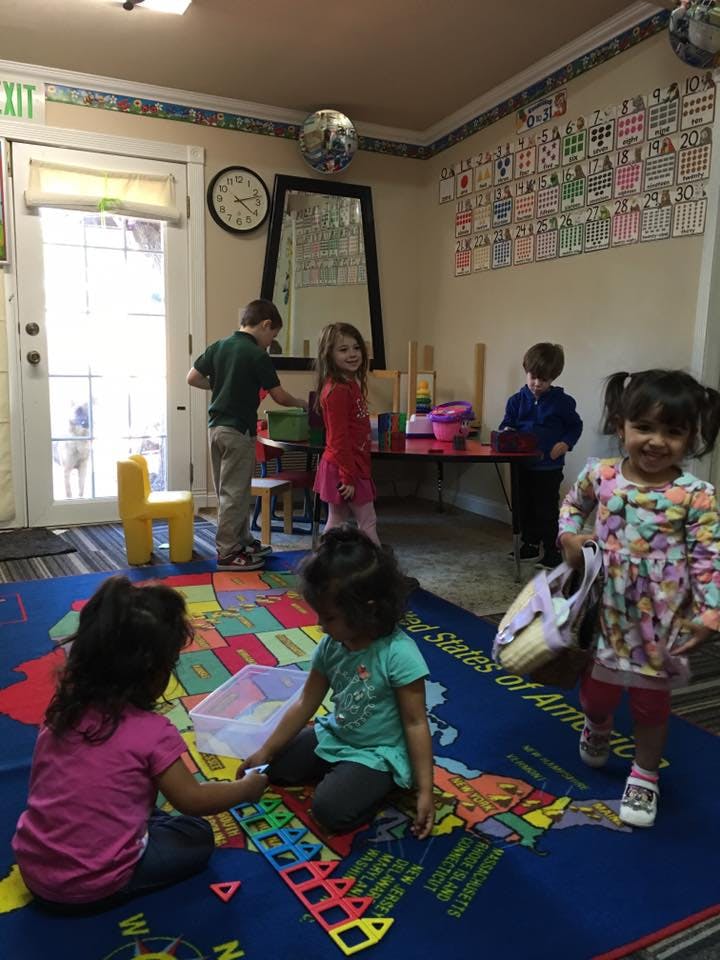 Children playing in a classroom with a map rug