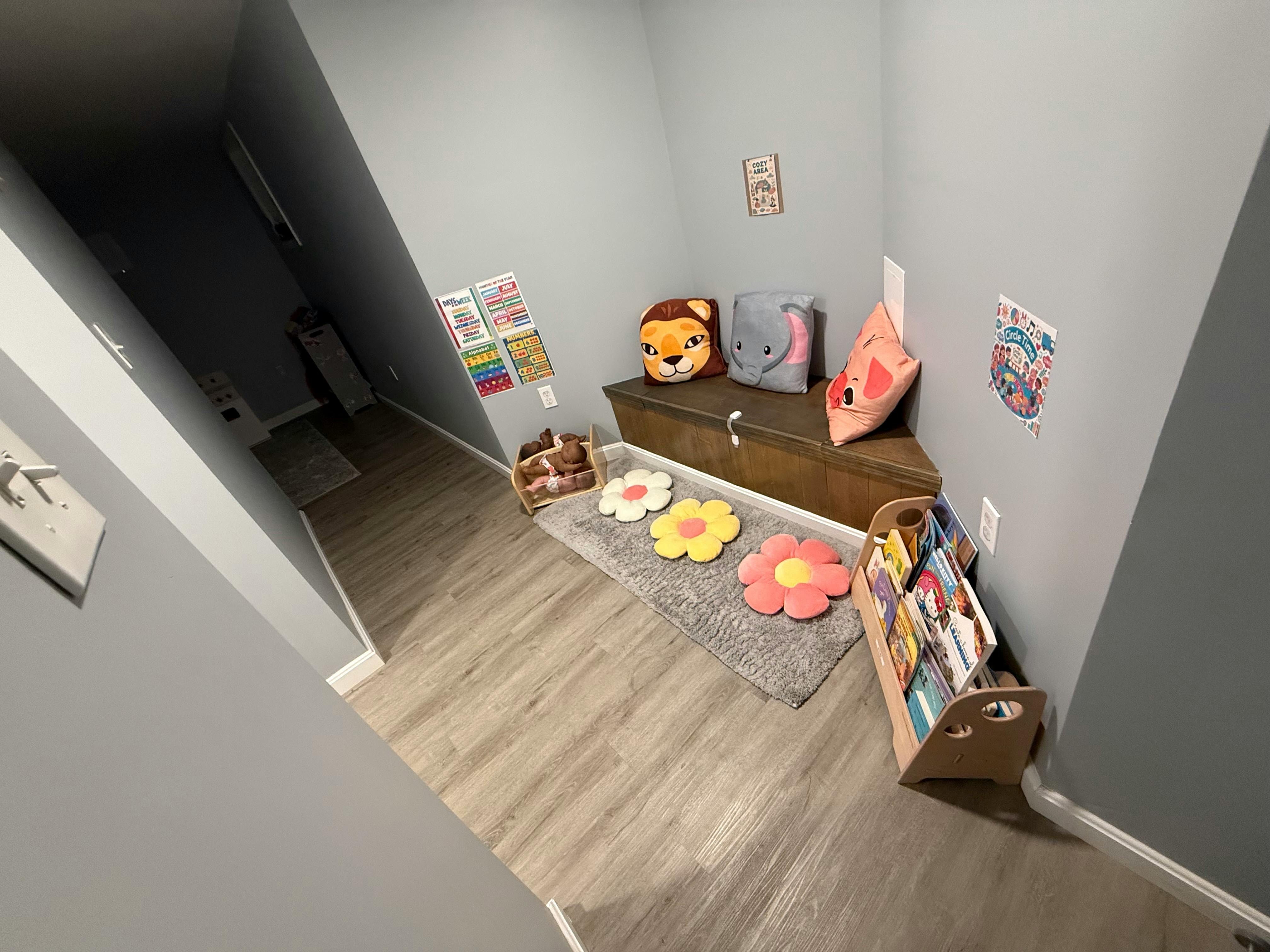 Children's reading nook with a bench, pillows, rug, and book display