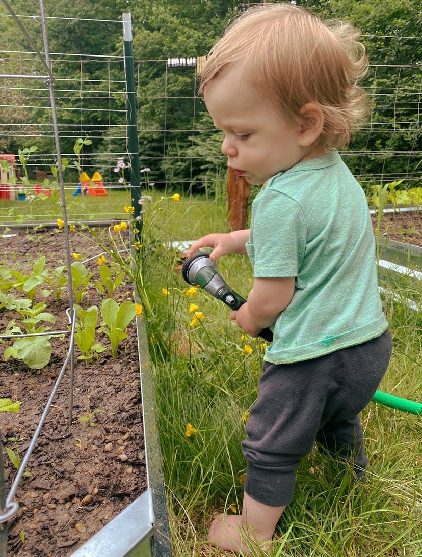 Child holding a hose in a garden