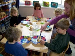 Adult serving food to children at a table