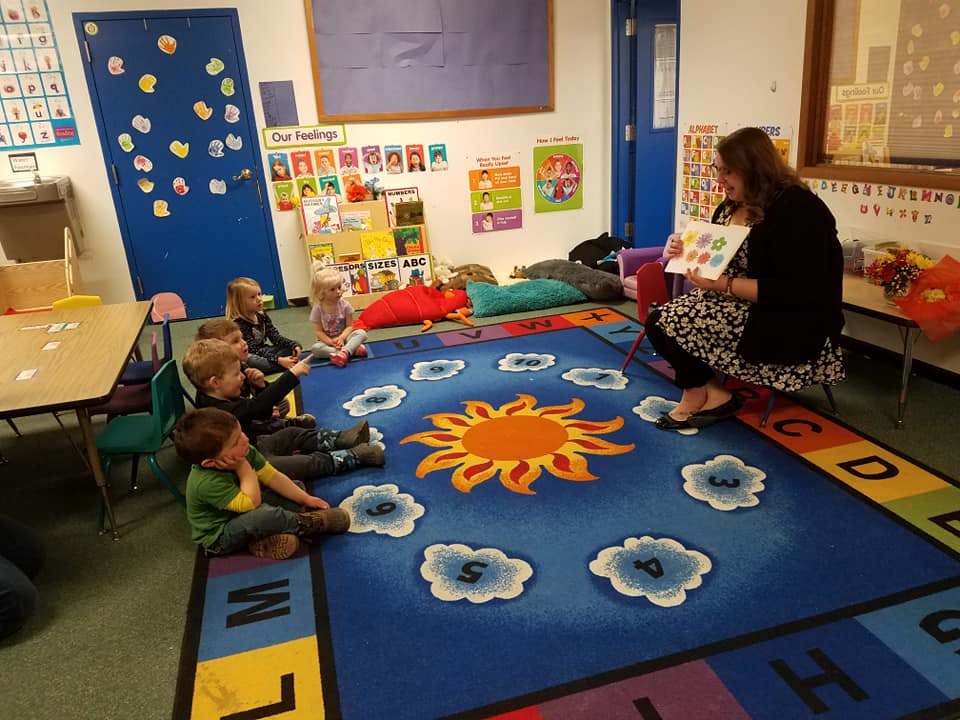 Adult reading a book to children in a classroom