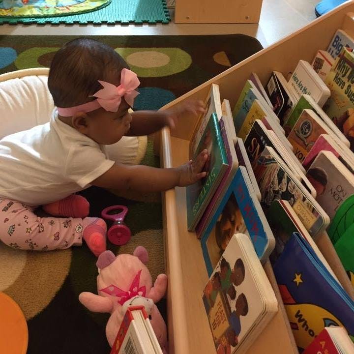 Child reaching for books in a wooden shelf