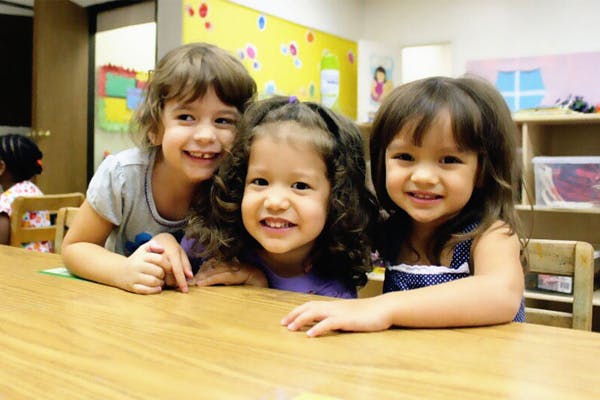 Three children sitting at a table in a classroom