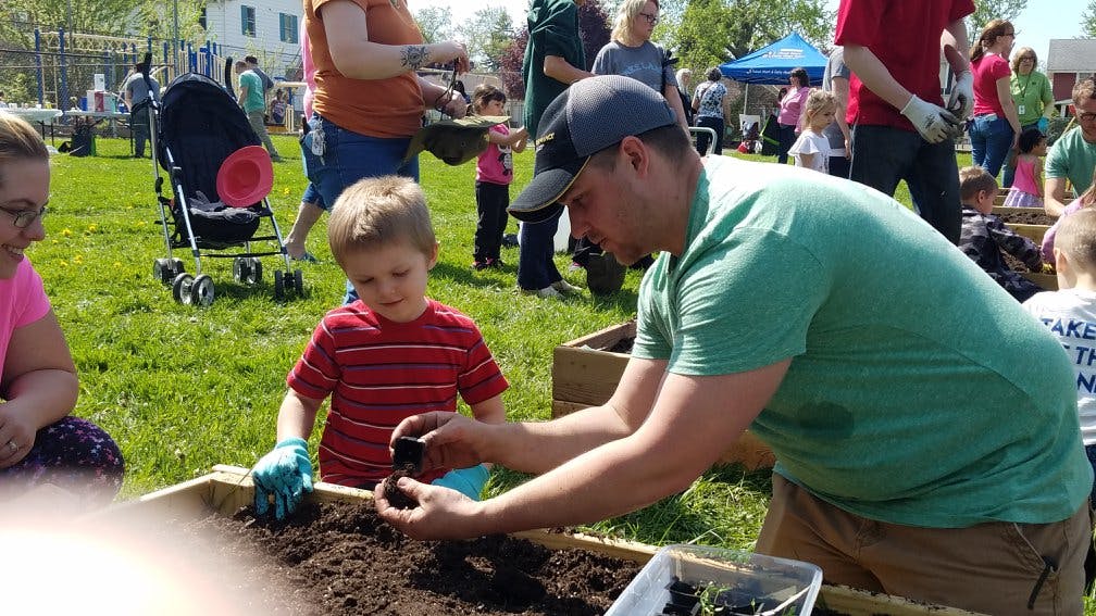 Adult and child planting in a raised garden bed