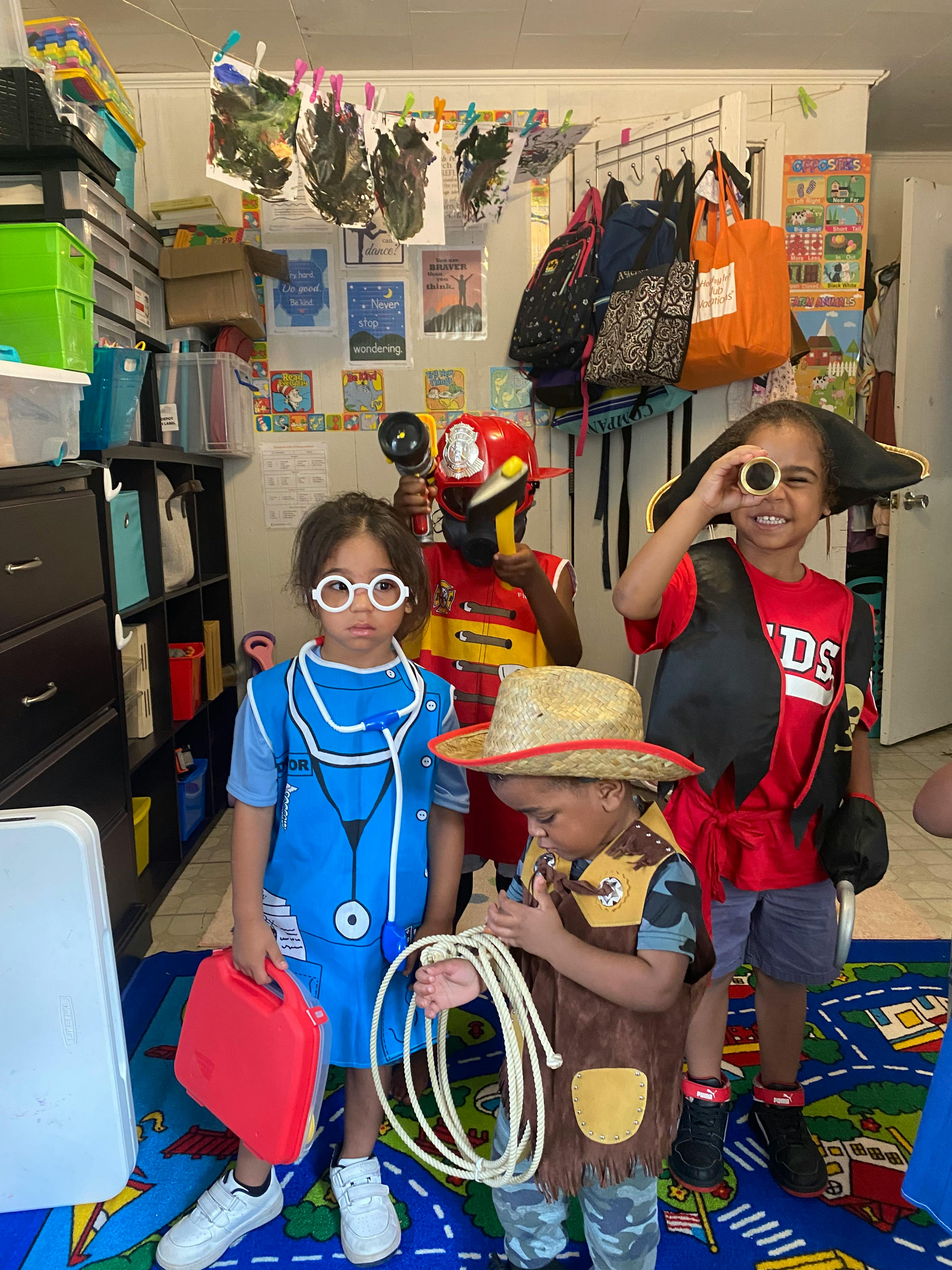 Four children in various costumes, including a doctor, firefighter, pirate, and cowboy