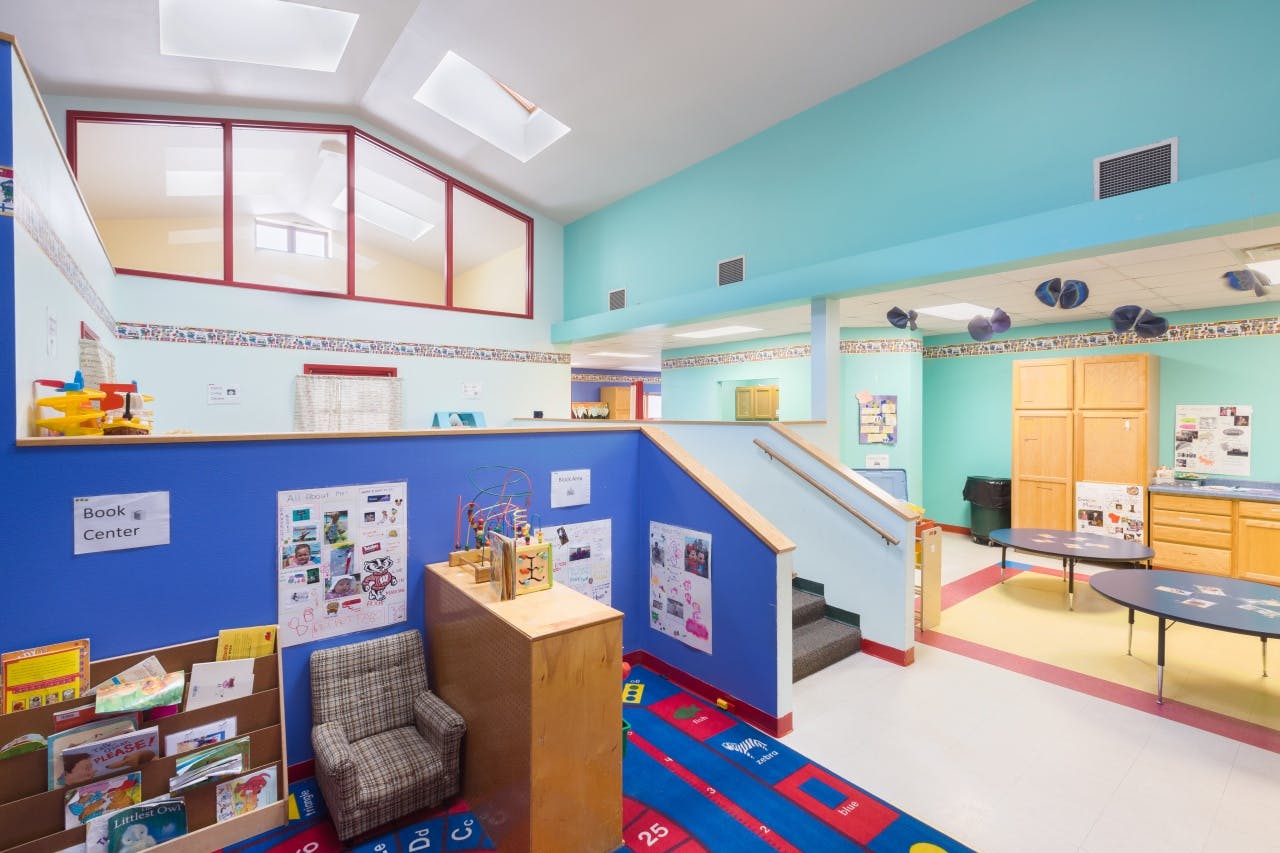 Playroom with blue walls, a staircase, and colorful rugs
