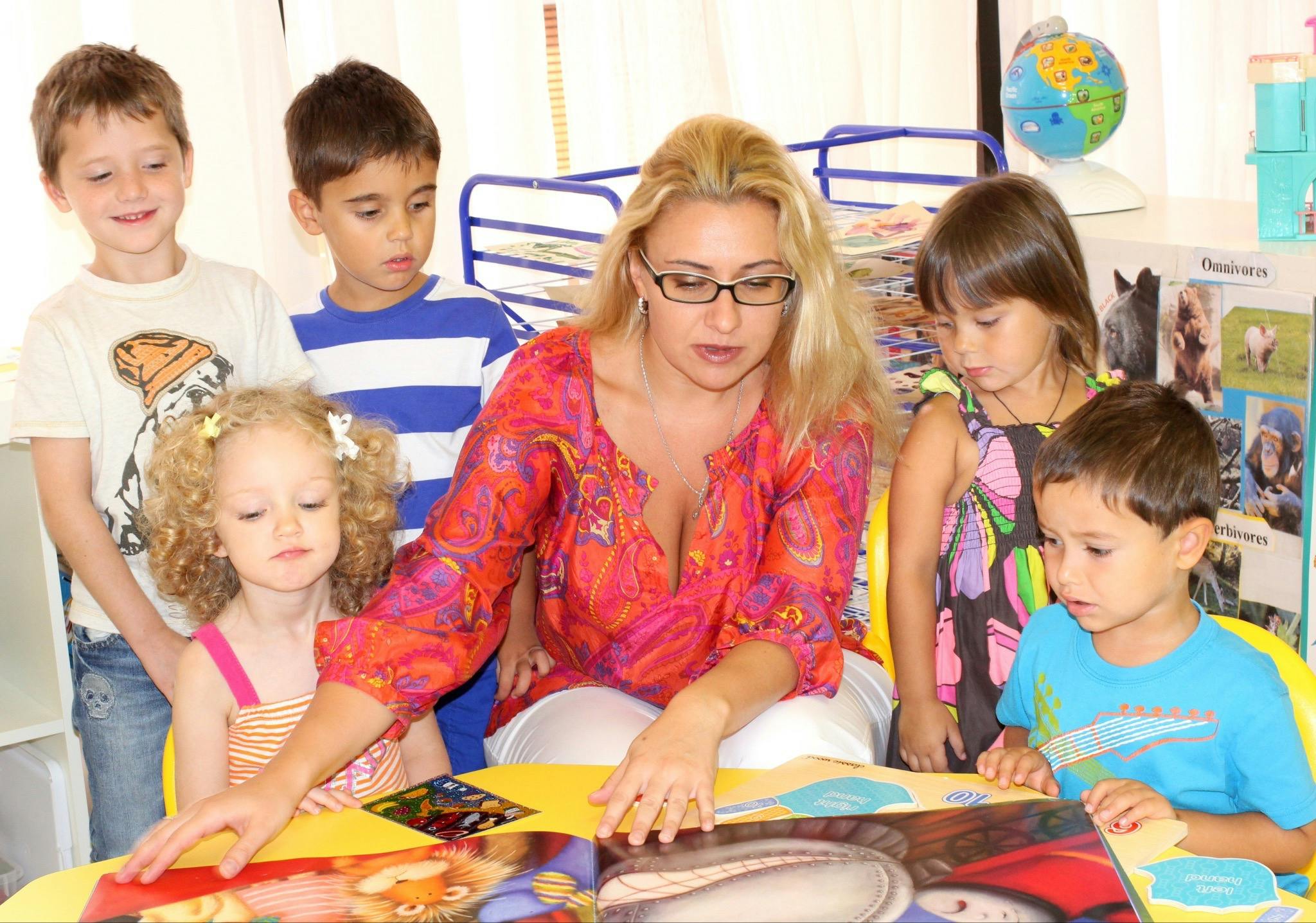 Person reading a book to multiple children in a classroom