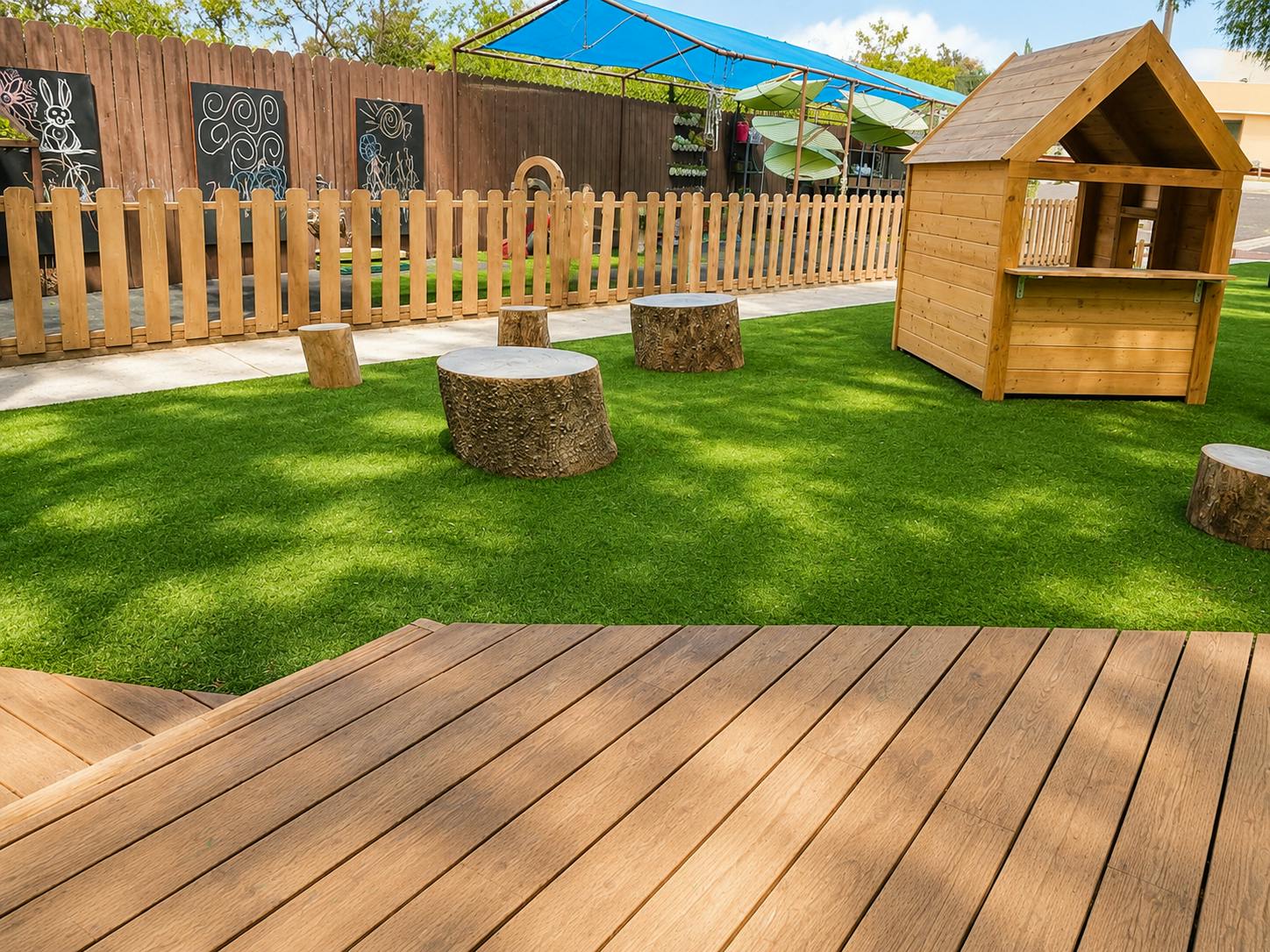 Wooden playhouse and tree stump stools on a playground with artificial turf
