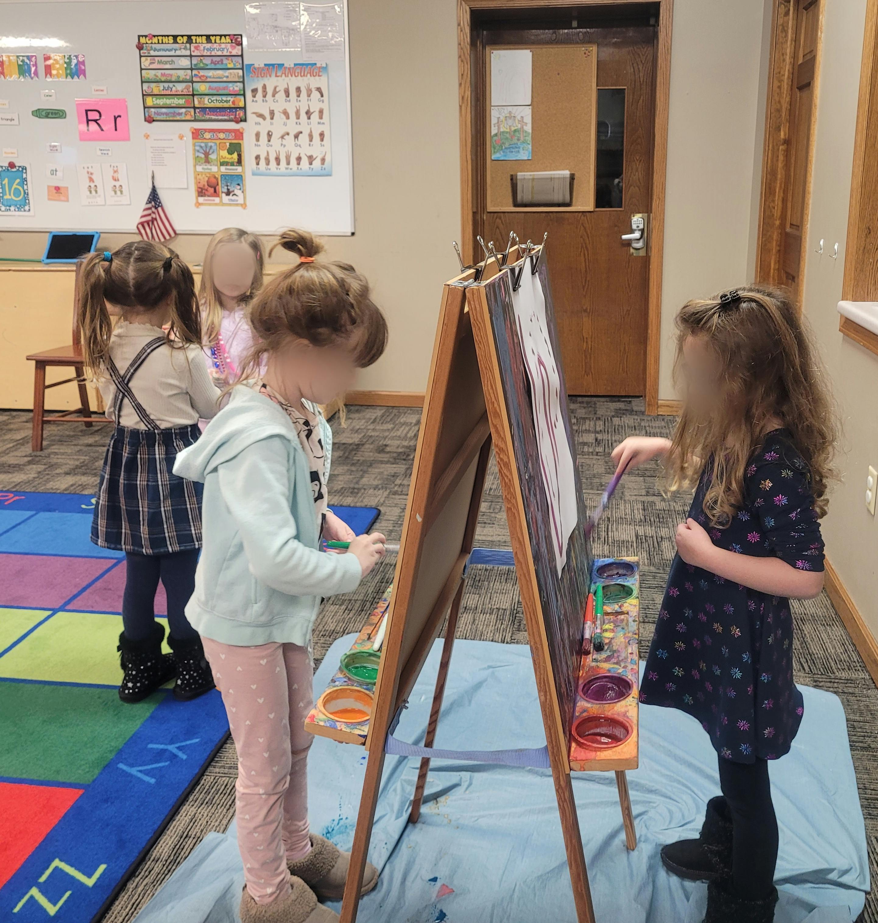 Children painting at an easel in a classroom