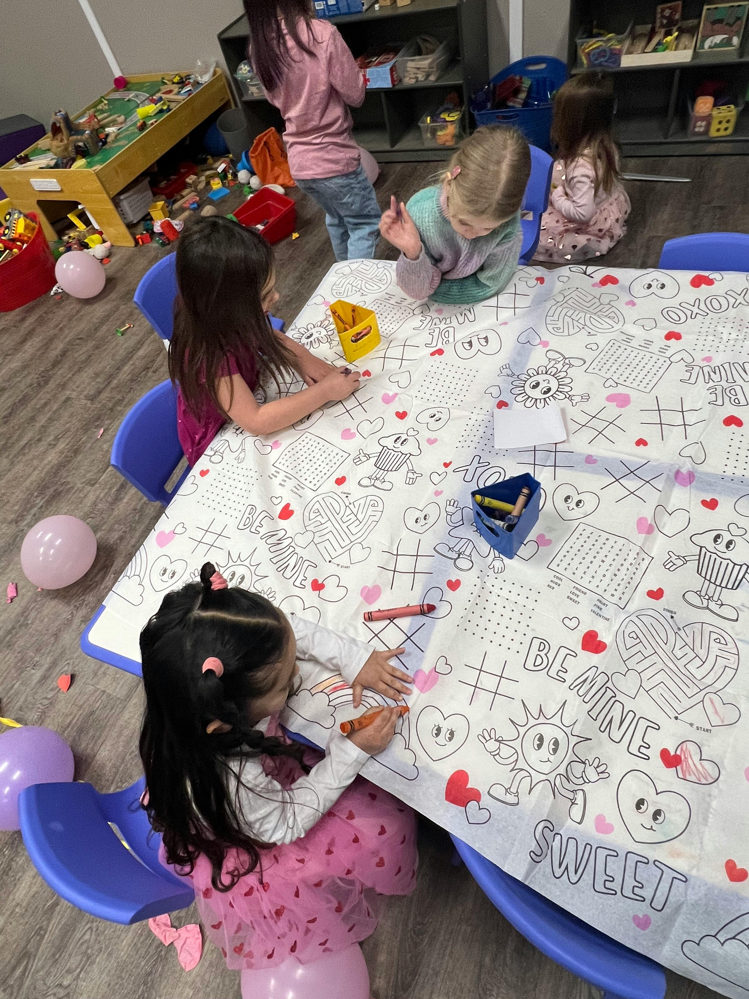 Children coloring at a table with a large coloring sheet